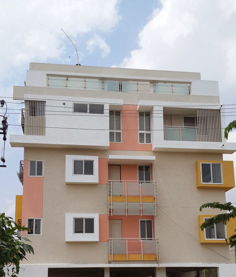 Peach, yellow and white apartment building with a glass-railed rooftop terrace
