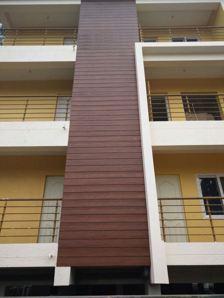 Apartment building with a vertical wood-finish feature wall and yellow balconies